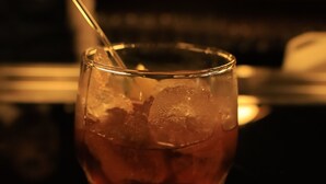 A glass with a straw and ice cubes on a reflective surface.