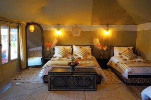 A bedroom with two beds, a decorative wall hanging, and a nightstand with a vase. - Young Luxury Camp Merzouga (Errachidia Province)