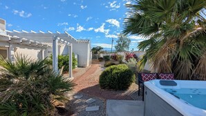 A patio area with a hot tub, a pergola, and a gravel path leading to a house.