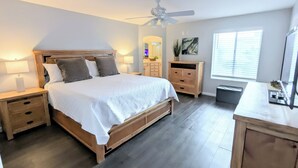 A bedroom with a wooden bed, nightstands, a dresser, a ceiling fan, and a window with blinds.