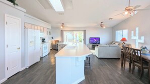 A modern kitchen with white cabinets, a central island, and a dining area with wooden chairs and a table.