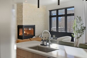 Una cocina moderna con chimenea integrada, un ventanal grande y una encimera blanca.