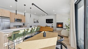 Eine moderne Küche mit einer zentralen Kochinsel, einem Essbereich mit Stühlen, einer Couch und einem Kamin.
