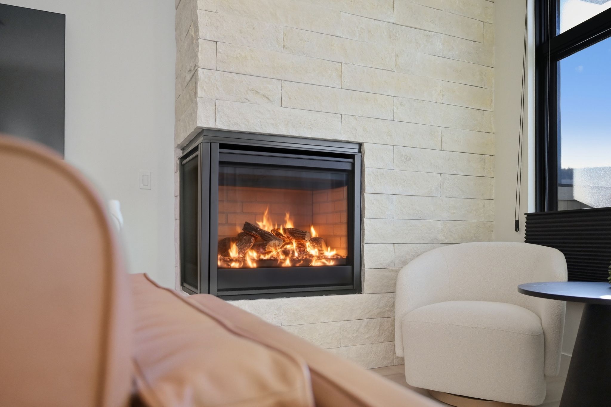 A modern living room with a fireplace, a sofa, a chair, and a small table.