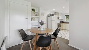 A compact kitchen with white cabinets, a microwave, and a refrigerator. - Wanaka Central Holiday Escape (Wanaka)