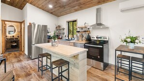 Una cocina moderna con techo de madera, electrodomésticos de acero inoxidable y una isla central con taburetes.