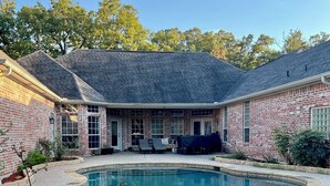 A brick house with a pool, stone wall, and patio furniture. - Beautiful Custom 4 bed with pool home with 3 acres. Private spacious backyard. (Campbell)