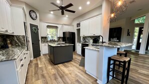 A spacious kitchen with white cabinets, a large island, and a dark floor. - Beautiful Custom 4 bed with pool home with 3 acres. Private spacious backyard. (Campbell)