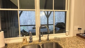 Eine Küche mit doppelter Spüle, einer Arbeitsplatte aus Granit und einem Fenster über der Spüle.