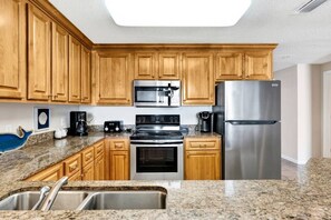 A kitchen with wooden cabinets, stainless steel appliances, granite countertops, and a built-in microwave.