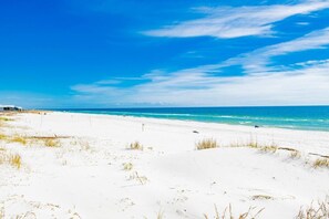 Une plage de sable blanc, un ciel bleu azur et l’océan.