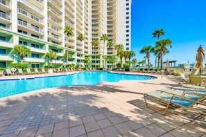 Um hotel com piscina, espreguiçadeiras e palmeiras.