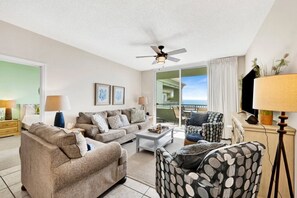 A living room with a sofa, armchair, coffee table, and a ceiling fan.