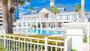 A resort with a swimming pool, white fences, and palm trees.