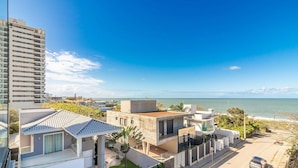 Una zona residenziale costiera con edifici moderni, un cielo azzurro limpido e vista sul mare.