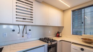 Una cucina funzionale con forno a incasso, lavatrice e finestra con persiane.