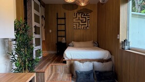 A compact bedroom with a bed, a wooden ladder, a wall-mounted artwork, and a window with a view of trees. - Studio JAPANDI in wonderful Miami with AC (Miami)