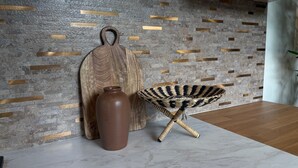 A modern interior with a stone wall, a wooden cutting board, a brown vase, and a woven chair. - Studio JAPANDI in wonderful Miami with AC (Miami)