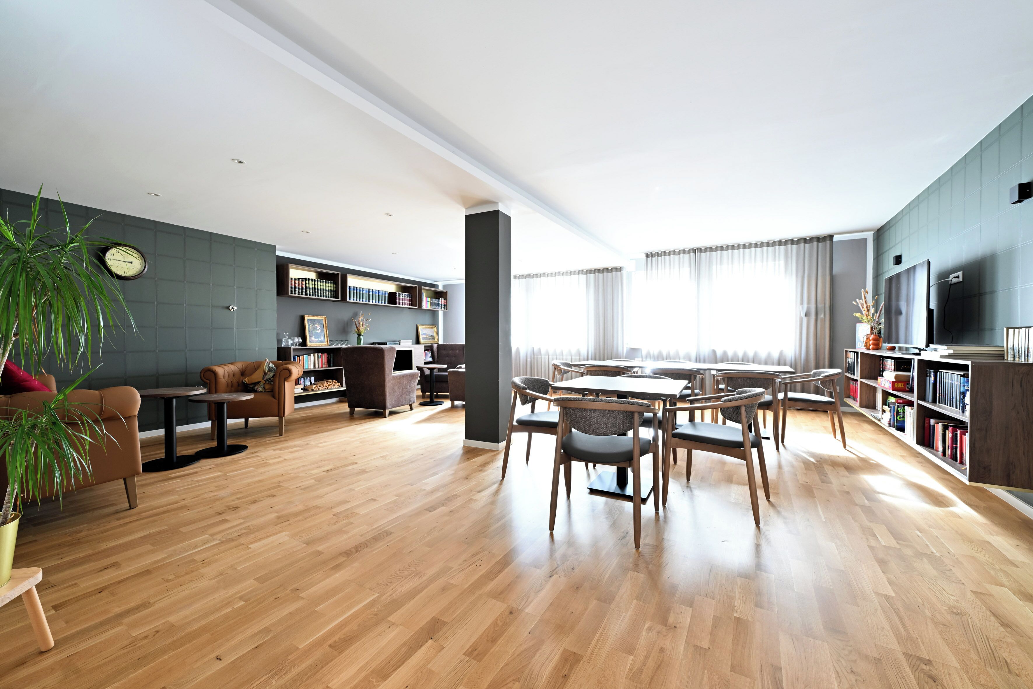 Un amplio espacio de sala con una mesa de comedor, sillas, un sofá y una estantería.