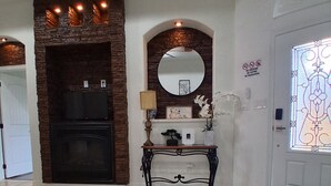 A spacious foyer with a fireplace, a console table with decorative items, a large mirror, and a tiled floor. - GORGEOUS HOME, COURTYARD, LANDSCAPPED, ABOVE GROUND POOL ,Outside barbecue area. (McAllen)