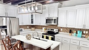 A modern kitchen with white cabinets, stainless steel appliances, and a central island. - GORGEOUS HOME, COURTYARD, LANDSCAPPED, ABOVE GROUND POOL ,Outside barbecue area. (McAllen)