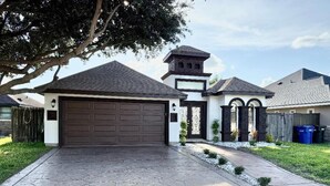 A residential house with a large garage, a stone driveway, and a small garden area. - GORGEOUS HOME, COURTYARD, LANDSCAPPED, ABOVE GROUND POOL ,Outside barbecue area. (McAllen)