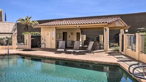 A swimming pool with lounge chairs and a covered patio area.