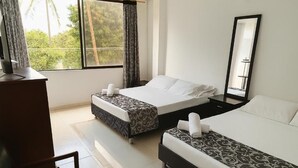 A hotel room with two beds, a desk, and a large window with curtains. - HOTEL AVENIDA 15 (Melgar)