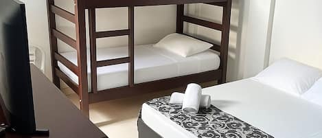Una habitación con dos literas, un escritorio con computadora y una colcha estampada.