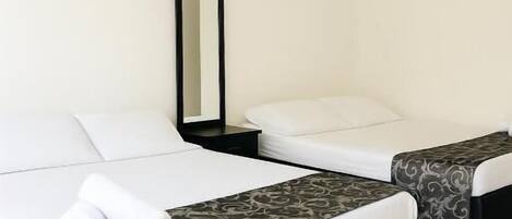 A hotel room with two beds, a large mirror, and a ceiling fan.