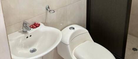 Un baño con lavamanos, inodoro y zona de ducha.
