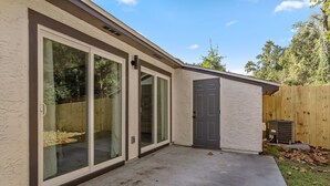 A house with a sliding glass door, a concrete patio, and a wooden fence. - LUXURY RENOVATED TOWNHOUSE CLOSE I-10 (Tallahassee)