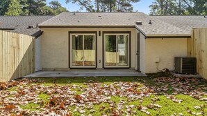 A residential building with a covered patio area, a wooden fence, and a lawn with fallen leaves. - LUXURY RENOVATED TOWNHOUSE CLOSE I-10 (Tallahassee)