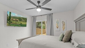 A bedroom with a bed, a ceiling fan, a painting, and a view of the outdoors. - LUXURY RENOVATED TOWNHOUSE CLOSE I-10 (Tallahassee)