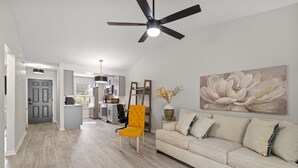 A modern living room with a beige sofa, a yellow chair, and a ceiling fan. - LUXURY RENOVATED TOWNHOUSE CLOSE I-10 (Tallahassee)