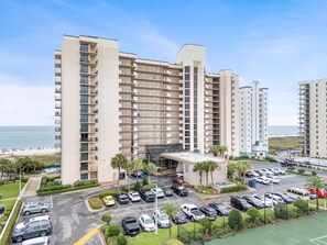A multi-story hotel with a parking lot and a beach view. - Phoenix East 101 (Orange Beach)