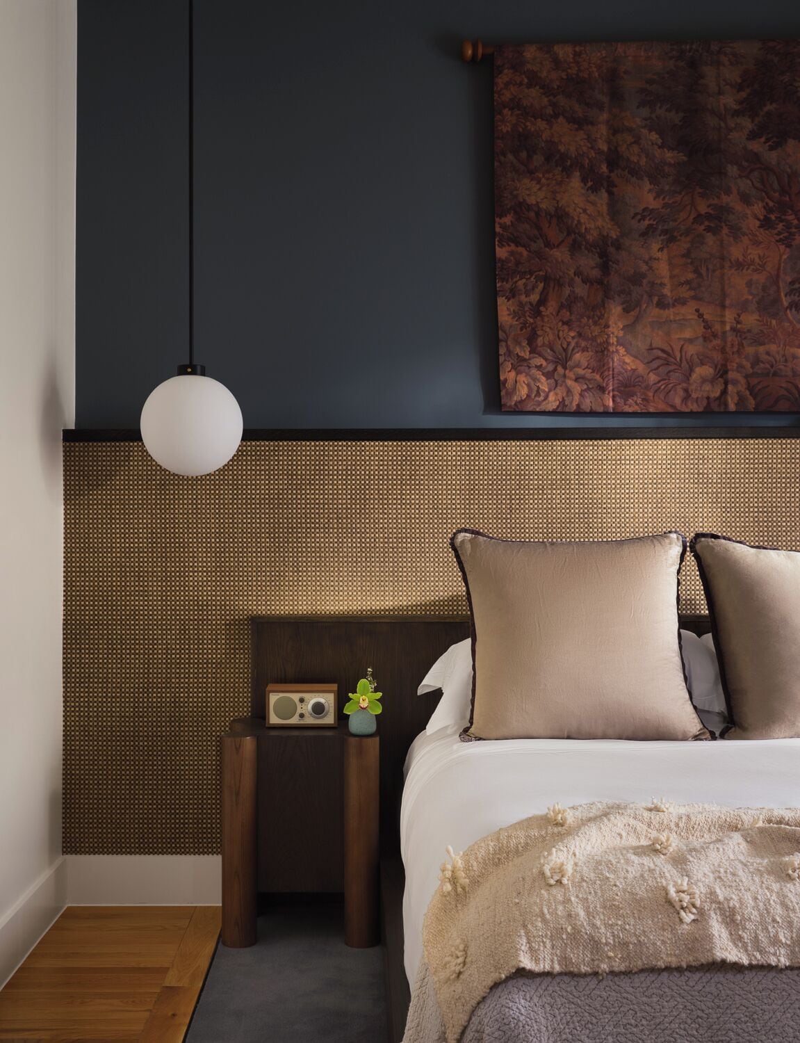 Une chambre à coucher avec un lit, une lampe suspendue, une radio et une petite plante.