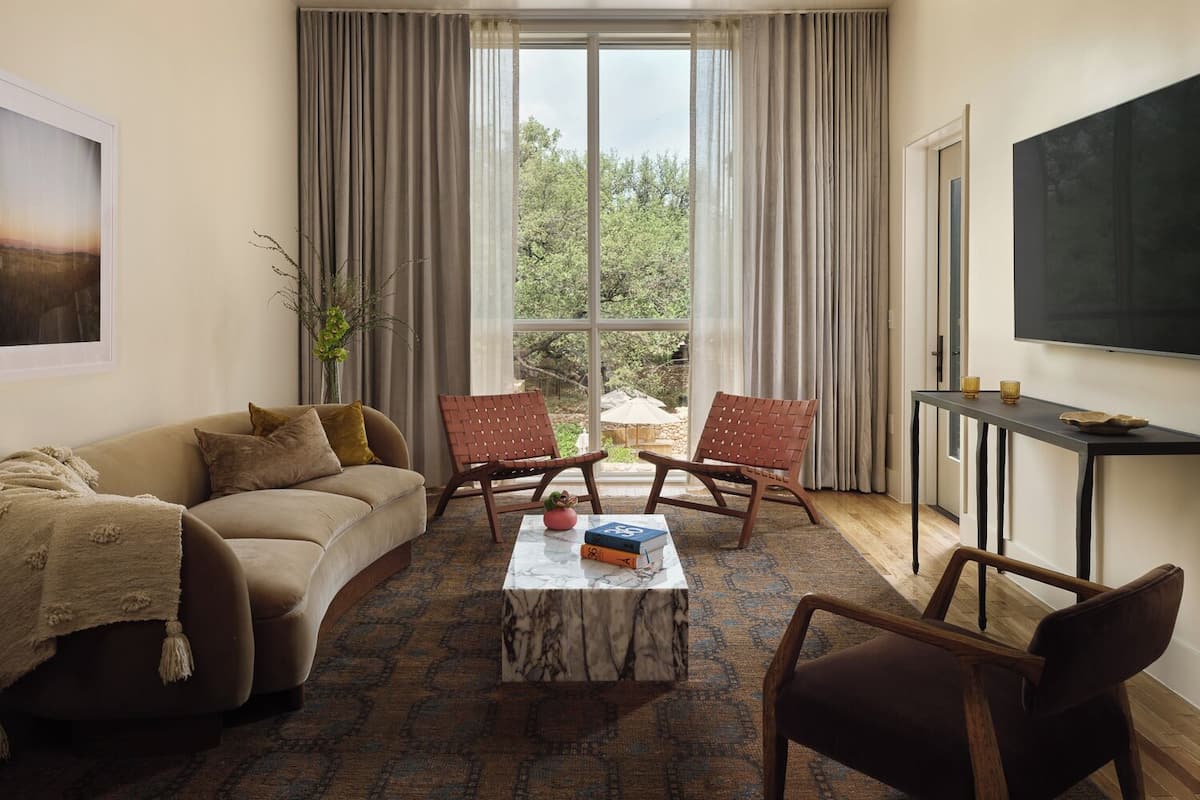 Un salon comprenant un canapé, deux fauteuils, une table basse et un téléviseur.
