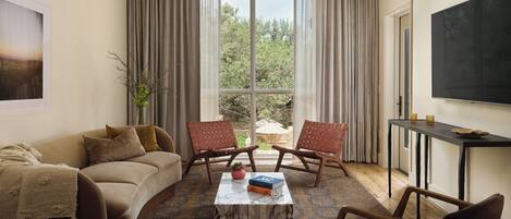 A living room with a sofa, two armchairs, a coffee table, and a TV.