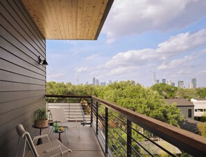 A balcony with a city skyline view, a wooden ceiling, and outdoor furniture.
