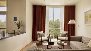 A modern living room with a sofa, chairs, a coffee table, and a view through large windows.