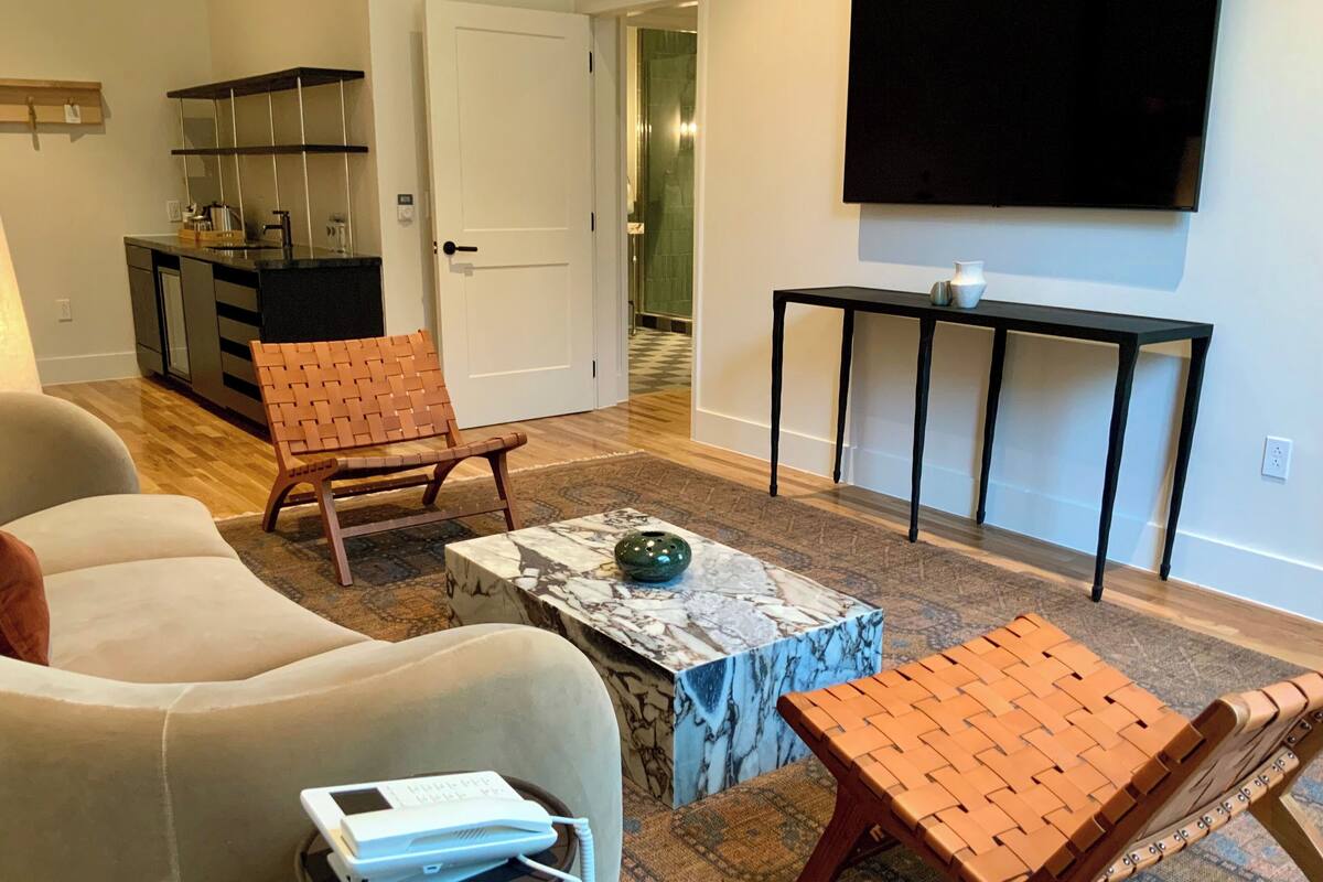 Un salon comprenant un canapé, une table basse, un téléviseur et une petite table sur laquelle est posé un vase.