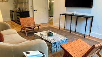A living room with a sofa, a coffee table, a TV, and a small table with a vase.