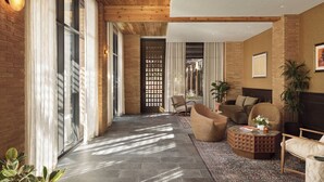 A spacious living area with a high ceiling, large windows, and a mix of seating arrangements including sofas and chairs. - The Inn at Green Pastures (Austin)