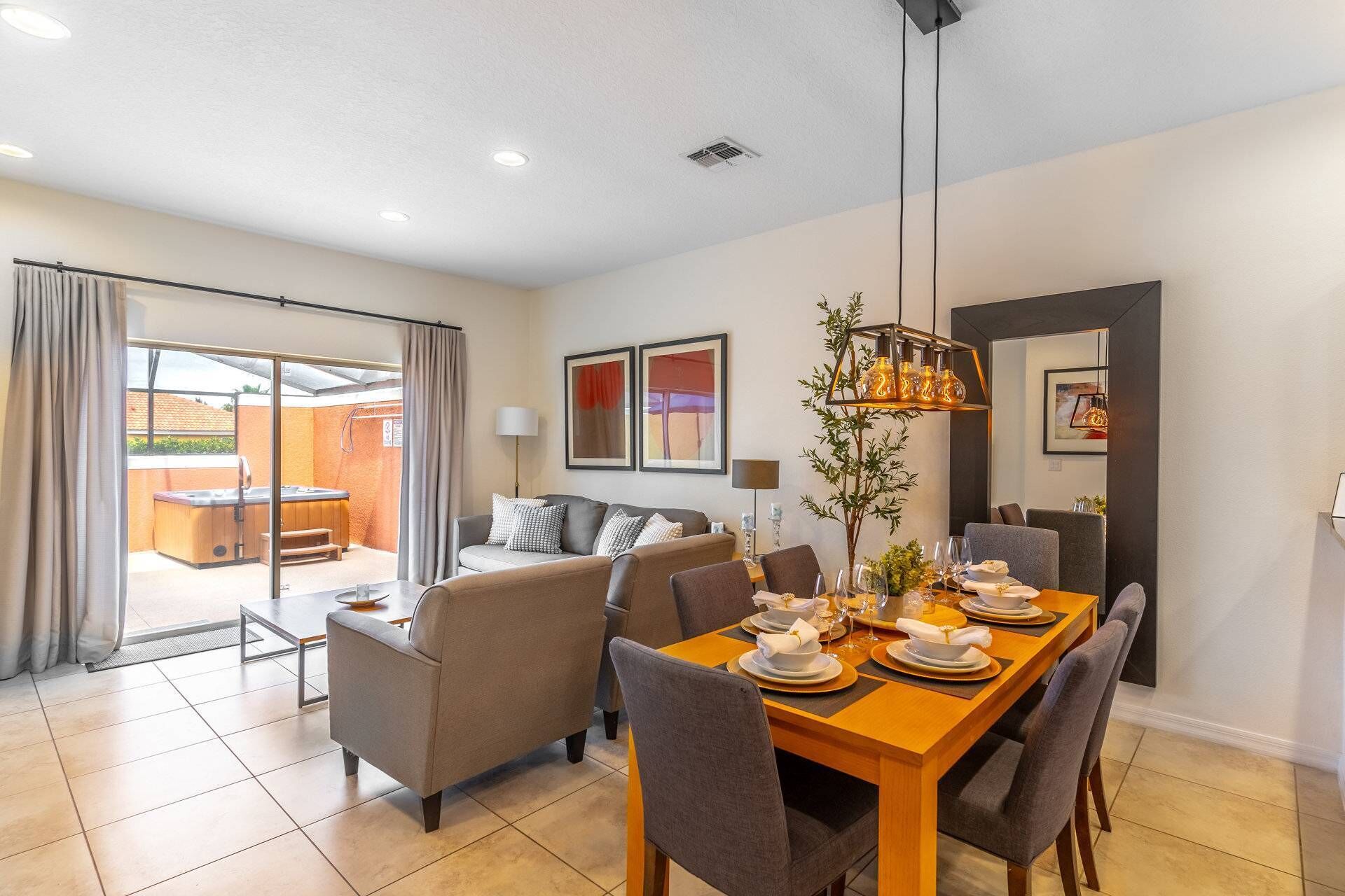 A modern dining area with a wooden table set for four, surrounded by grey upholstered chairs.