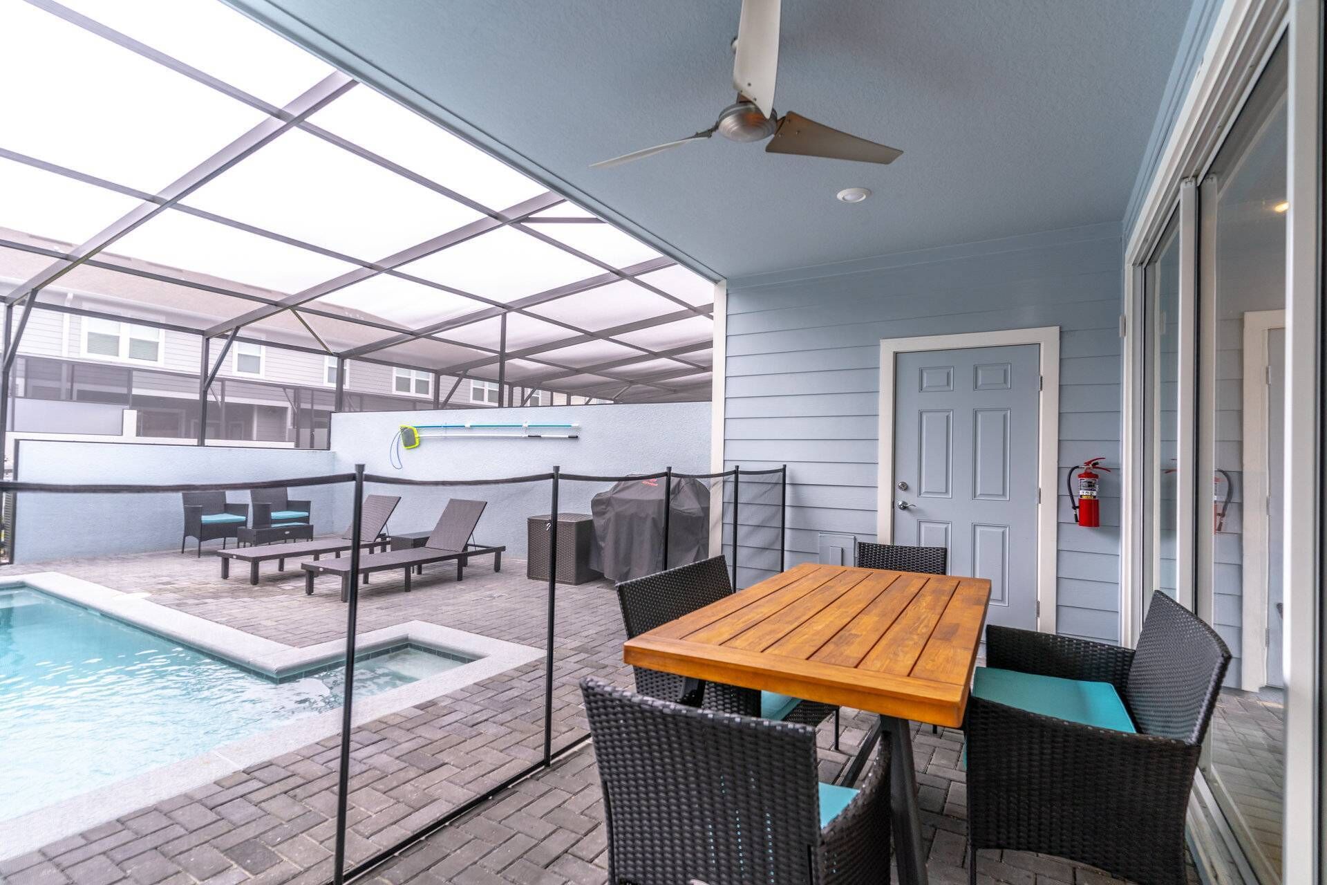 Eine überdachte Terrasse mit Pool, Sitzgelegenheit im Freien und Deckenventilator.
