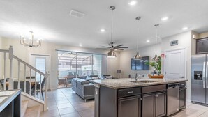 A modern kitchen with a central island, stainless steel appliances, and a ceiling fan. - 4014 Windsor Island (Davenport)