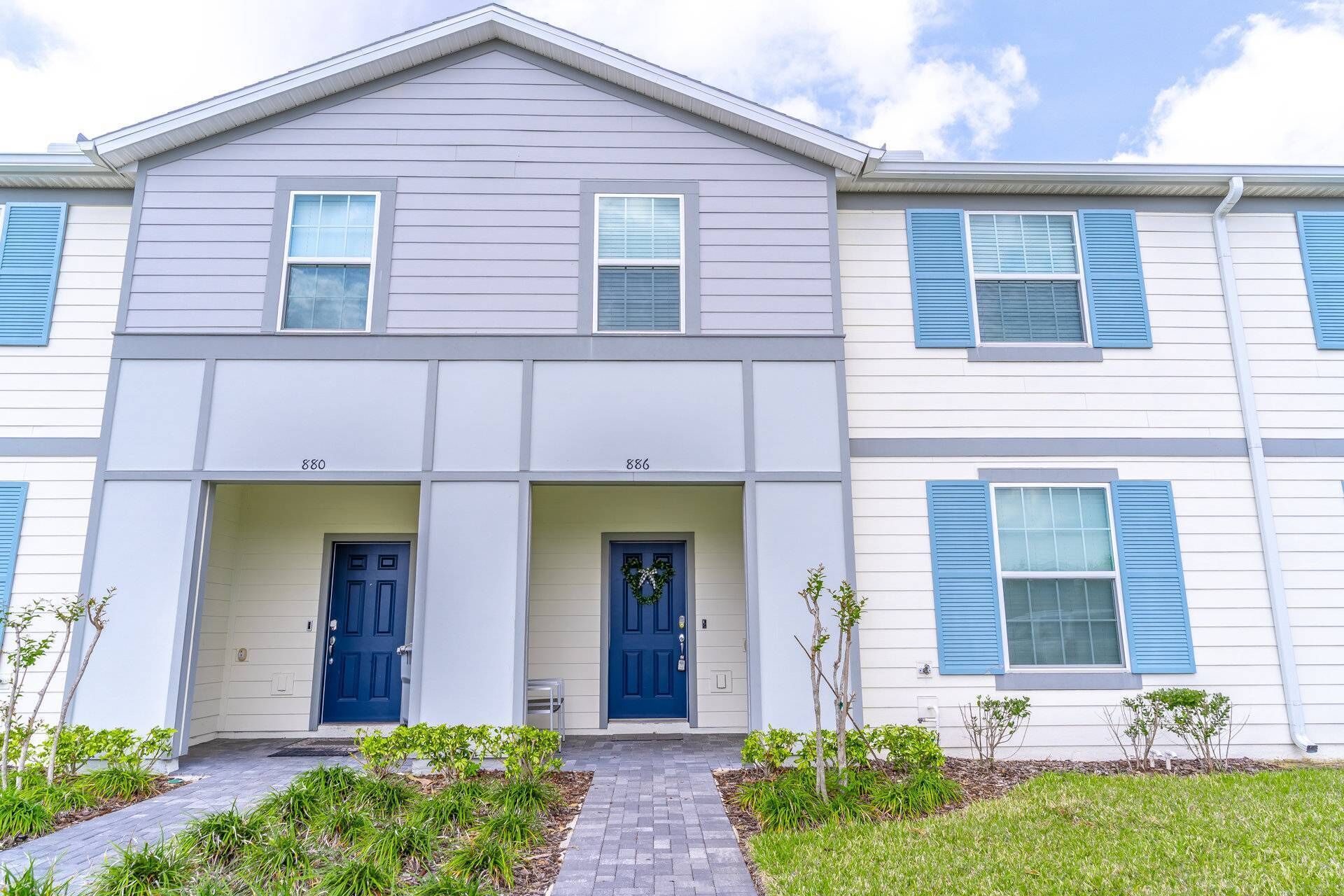 A two-story residential building with a symmetrical facade, numbered units 880 and 886, featuring a central entrance with double doors and a small porch area.