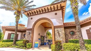 A hotel entrance with an arched gateway, stone facade, and palm trees. - 4763 Solterra (Davenport)