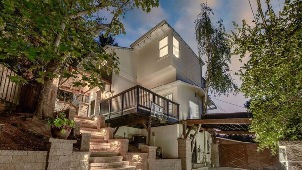 Une maison à deux étages avec un escalier en pierre menant à un balcon.